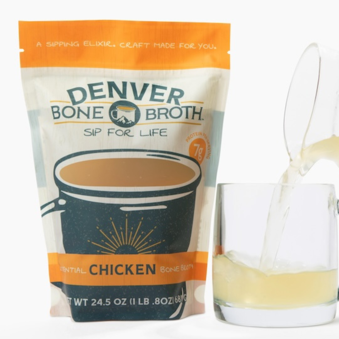 A front facing pouch of Denver Bone Broth's healthy Essential Chicken flavor. Next to the pouch, there is a small glass mug with the healthy, natural bone broth being poured into it.